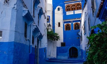 a narrow alleyway with blue painted buildings