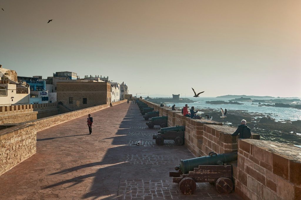 A long wall overlooks the ocean and the city.