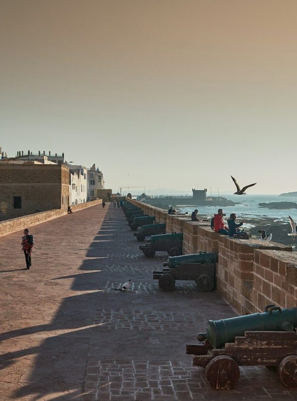A long wall overlooks the ocean and the city.